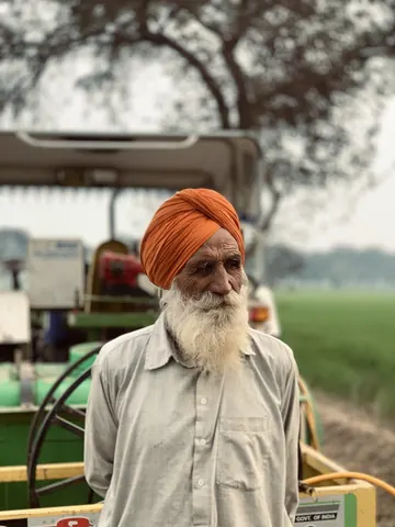 An orange turban against the green of the fields.