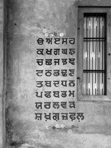 Gurmukhi letters keep their place on a weathered wall.