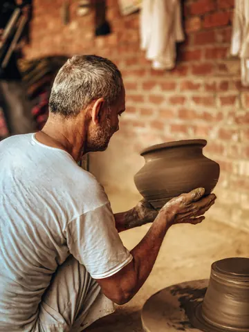 A clay vessel taking shape in a potter's hands.
