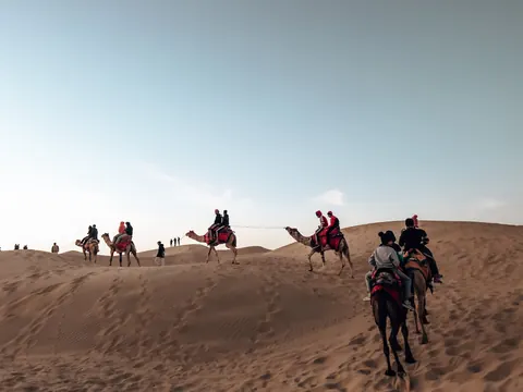 Riders crossing a ridge beneath an open sky.