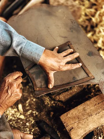 A close view of hands guiding a tool across the workbench.