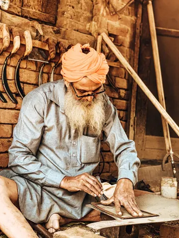 An orange turban, a quiet workshop, and careful hands.
