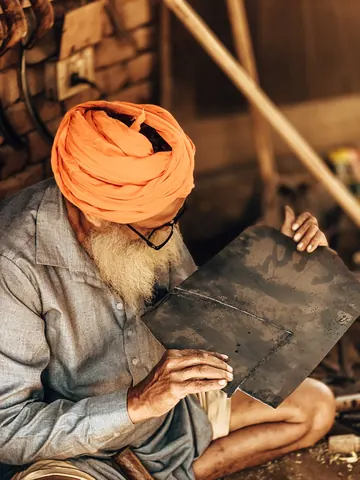 Checking an edge in the warm light of the workshop.