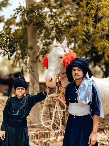 Two young companions beside a decorated white horse.