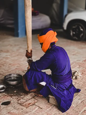 An orange turban and blue robes beside a wooden mortar.