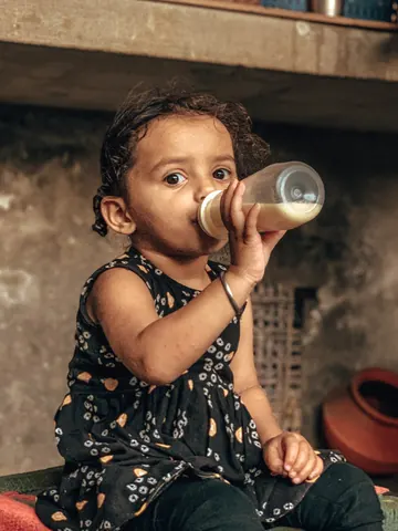 A small child pauses for a drink.