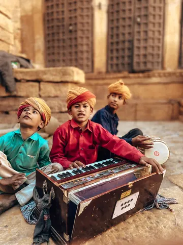 Young musicians gather around a harmonium.