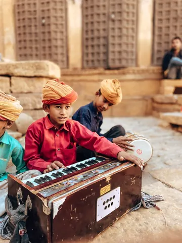 Small hands at the harmonium, with rhythm close by.