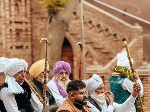 A gathering of elders, bright turbans, and raised walking sticks.