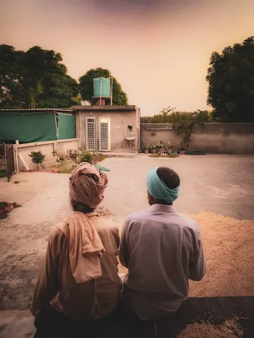 Two figures walk together along a quiet village lane.