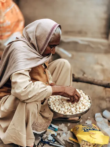 An elder sorts a tray of small white pieces.