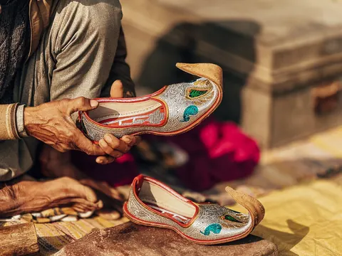 A pair of embroidered shoes, held up for a closer look.