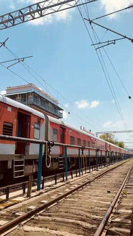 Red carriages and railway lines beneath a wide blue sky.