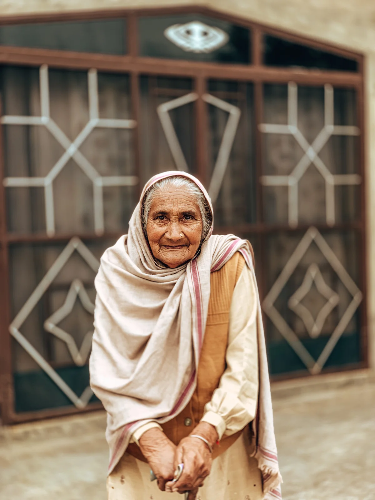 An elder woman standing outside her home